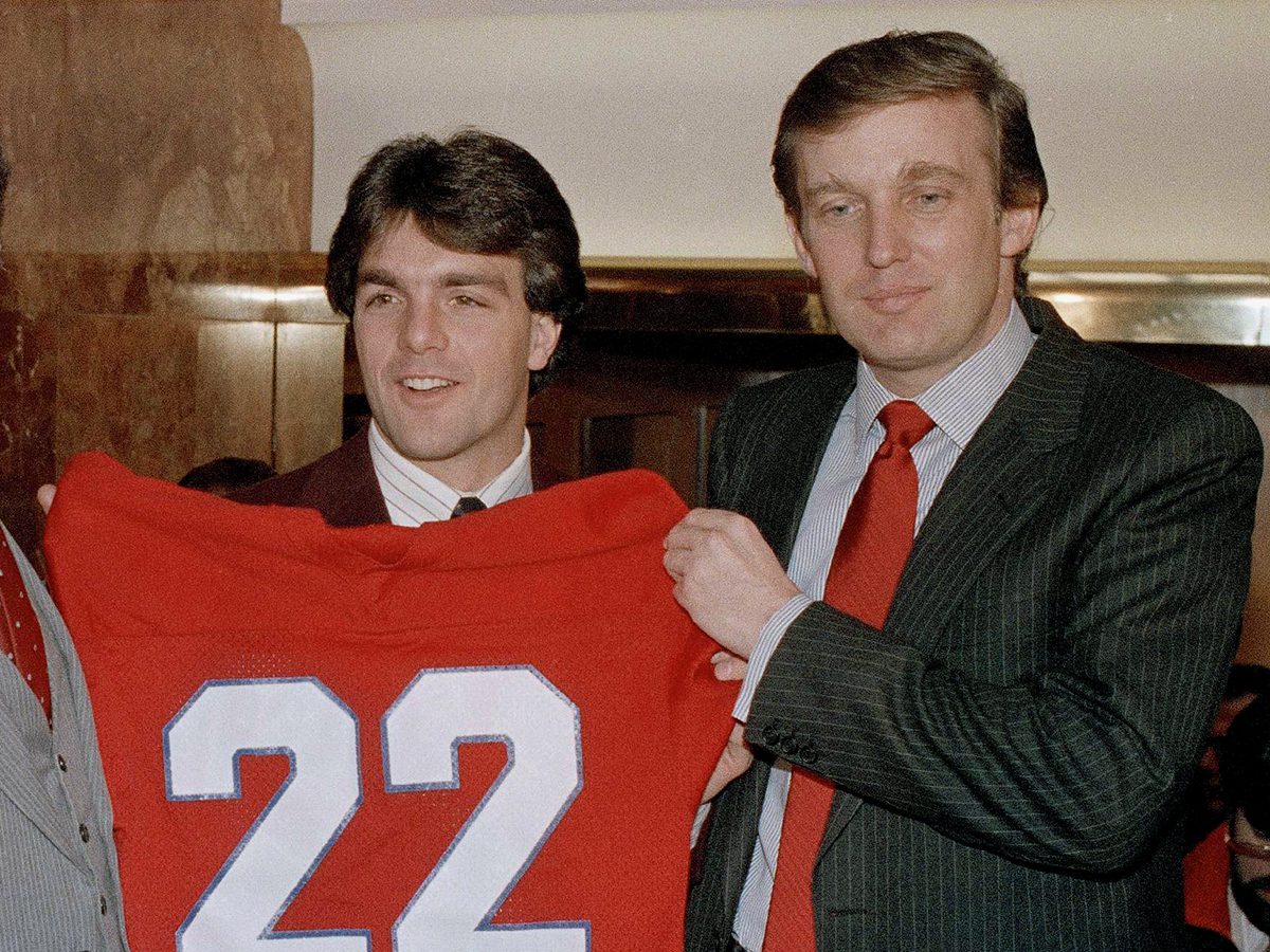 Boston College quarterback Doug Flutie poses with New Jersey Generals head coach Walt Michaels, left, and General's owner, Donald Trump, at a news conference in New York, Feb. 5, 1985. An official announcement was made that Flutie signed a multi-million-dollar pact with the USFL team. (AP Photo/Marty Lederhandler)